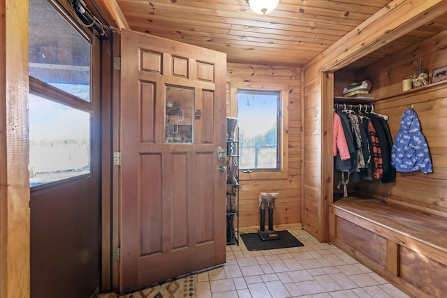 mudroom with wood ceiling, light tile patterned flooring, and wood walls