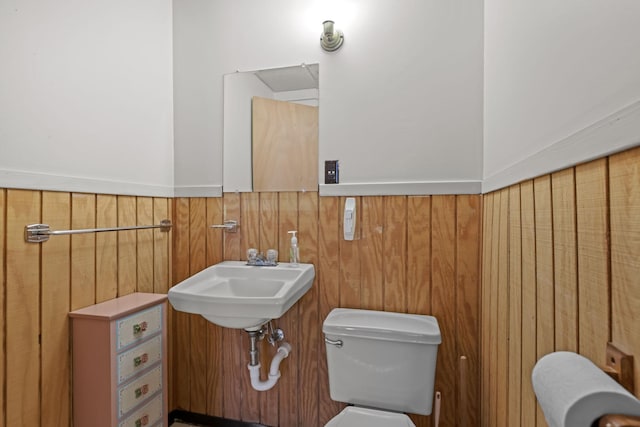 bathroom with sink, wooden walls, and toilet