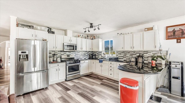 kitchen featuring white cabinetry, tasteful backsplash, a textured ceiling, appliances with stainless steel finishes, and kitchen peninsula