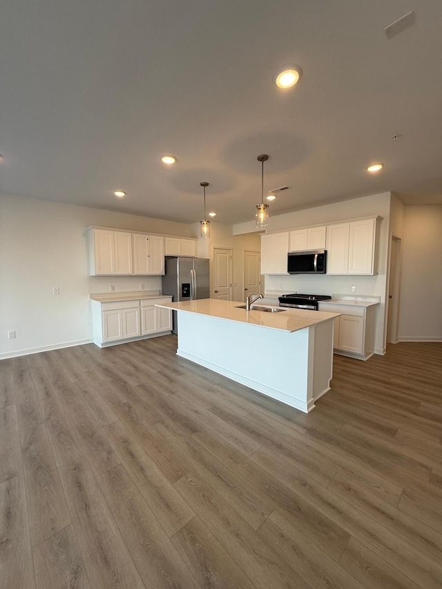 kitchen with sink, white cabinetry, a center island with sink, pendant lighting, and stainless steel appliances