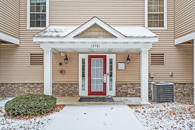 snow covered property entrance with cooling unit