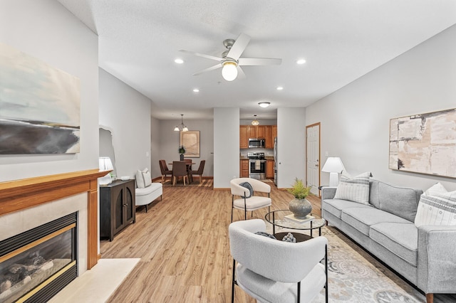 living room with ceiling fan, light hardwood / wood-style floors, and a tile fireplace