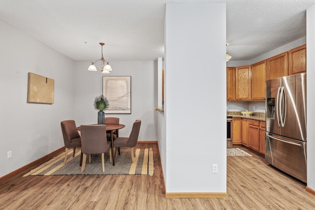 dining room featuring a textured ceiling, light hardwood / wood-style floors, and a chandelier