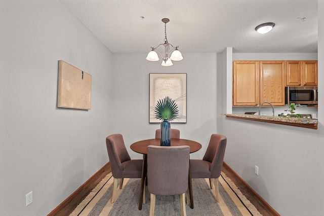 dining area featuring hardwood / wood-style floors, a notable chandelier, and a textured ceiling