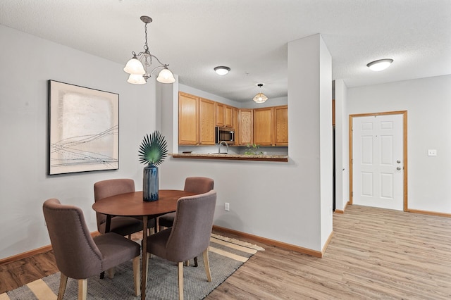 dining room featuring sink, a textured ceiling, and light hardwood / wood-style floors