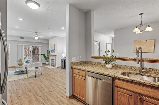 kitchen featuring a tile fireplace, sink, light stone counters, stainless steel appliances, and a textured ceiling