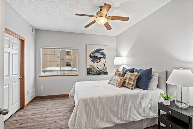 bedroom featuring ceiling fan, light hardwood / wood-style flooring, and a textured ceiling