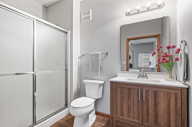 bathroom featuring vanity, hardwood / wood-style flooring, toilet, and walk in shower