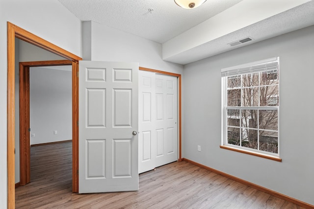 unfurnished bedroom with a closet, a textured ceiling, and light wood-type flooring