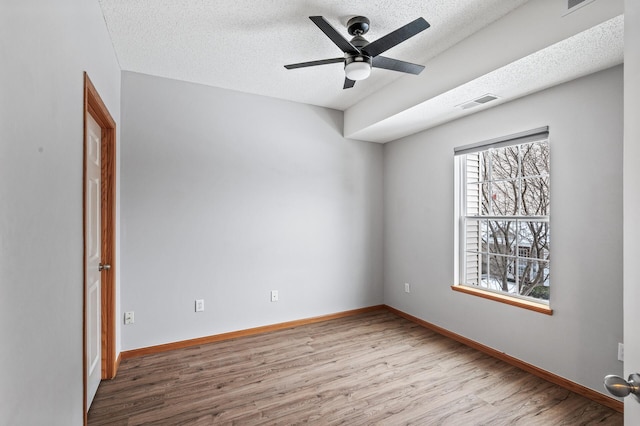 spare room with ceiling fan, light hardwood / wood-style floors, and a textured ceiling