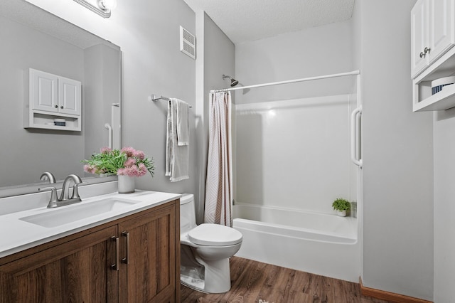 full bathroom featuring shower / bathtub combination with curtain, hardwood / wood-style floors, vanity, a textured ceiling, and toilet