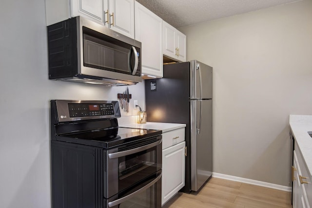 kitchen featuring a textured ceiling, light hardwood / wood-style flooring, stainless steel appliances, and white cabinets