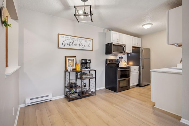 kitchen with stainless steel appliances, white cabinetry, a baseboard heating unit, and light wood-type flooring