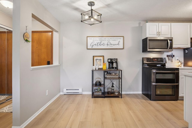 kitchen featuring pendant lighting, appliances with stainless steel finishes, light wood-type flooring, and white cabinets