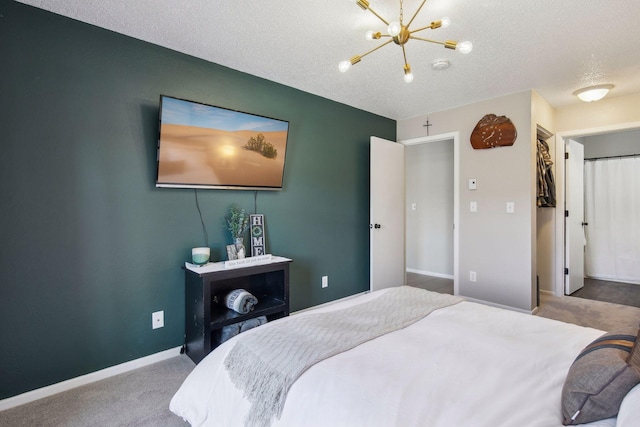 carpeted bedroom featuring a chandelier and a textured ceiling