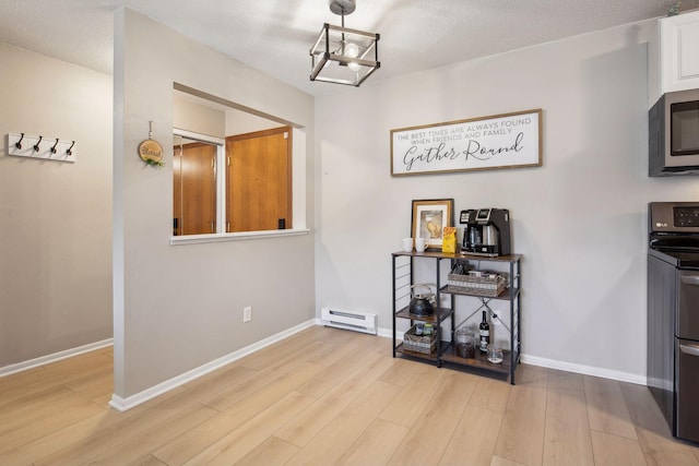 interior space featuring baseboard heating, light hardwood / wood-style floors, and a textured ceiling