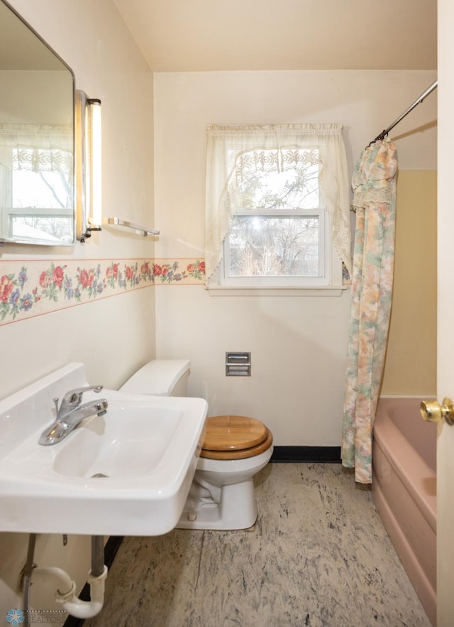 full bathroom featuring sink, shower / bath combo with shower curtain, and toilet