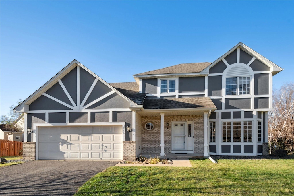 view of front of property featuring a front yard, brick siding, driveway, and an attached garage