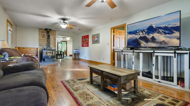 living room featuring hardwood / wood-style flooring, ceiling fan, and a wood stove