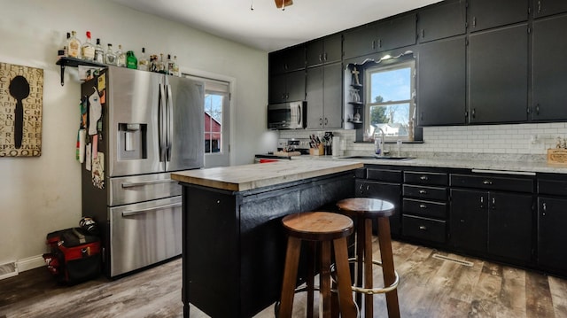 kitchen featuring tasteful backsplash, stainless steel appliances, sink, and a kitchen island