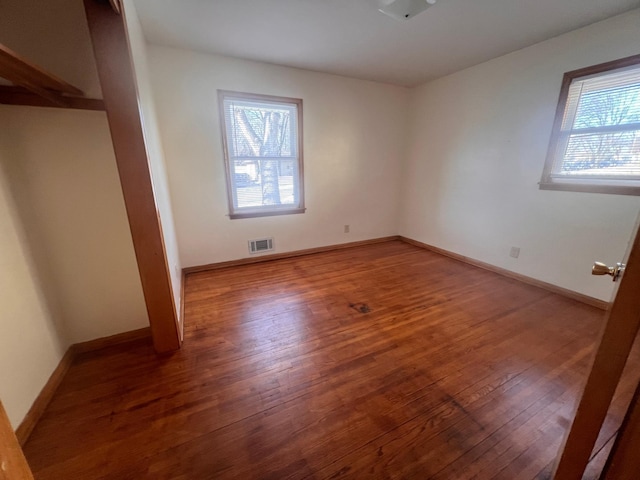 unfurnished room with plenty of natural light and dark hardwood / wood-style flooring