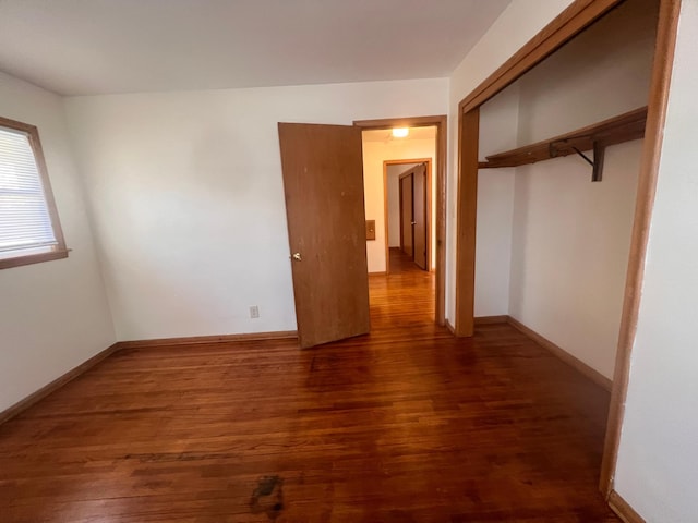 unfurnished bedroom featuring dark wood-type flooring and a closet