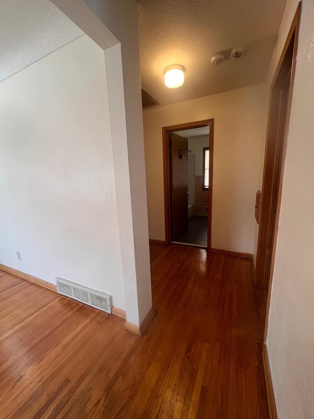 hallway featuring dark hardwood / wood-style flooring and a textured ceiling