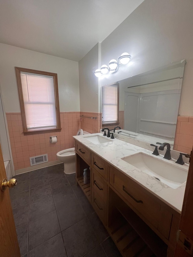 bathroom featuring tile patterned flooring, vanity, toilet, and tile walls