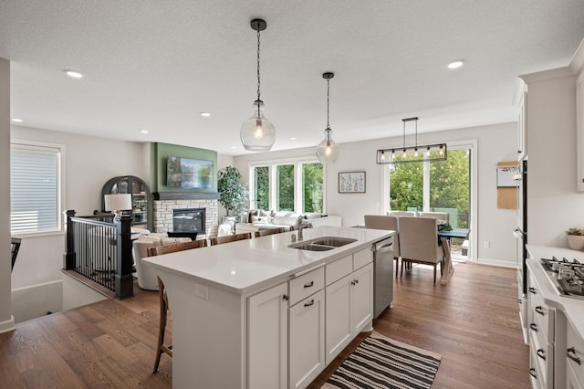 kitchen featuring white cabinetry, sink, a center island with sink, and pendant lighting