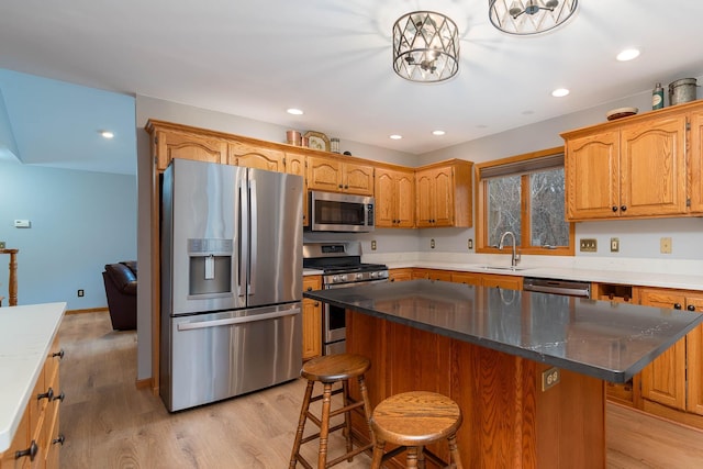 kitchen with appliances with stainless steel finishes, sink, a kitchen breakfast bar, a center island, and light hardwood / wood-style floors