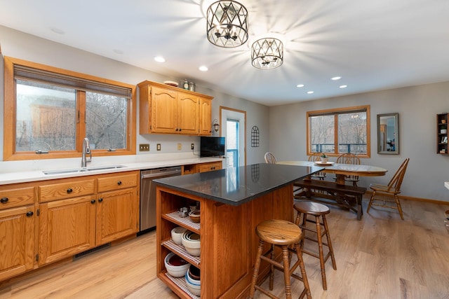 kitchen with stainless steel dishwasher, sink, a kitchen island, and light hardwood / wood-style flooring