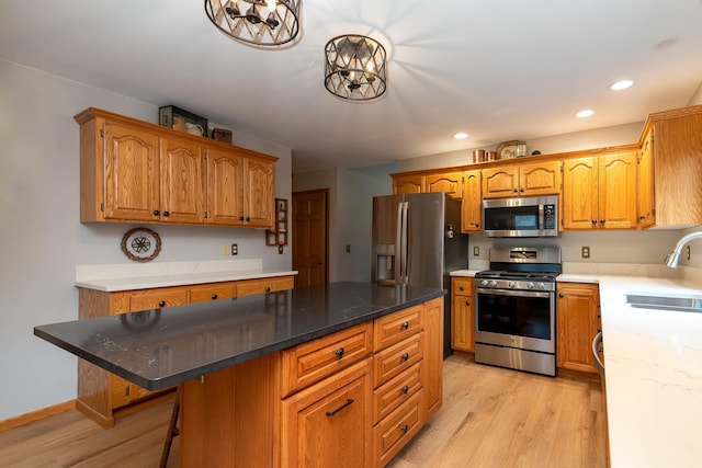 kitchen with sink, appliances with stainless steel finishes, a kitchen island, a kitchen bar, and light wood-type flooring