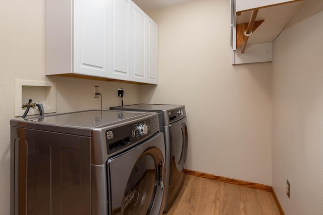 clothes washing area featuring cabinets, washing machine and clothes dryer, and light wood-type flooring