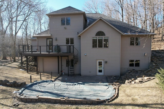 rear view of house with a wooden deck and a garage