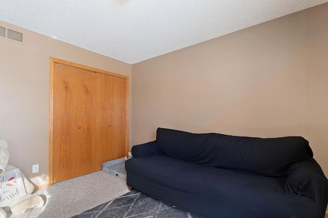 living area featuring dark colored carpet and a textured ceiling