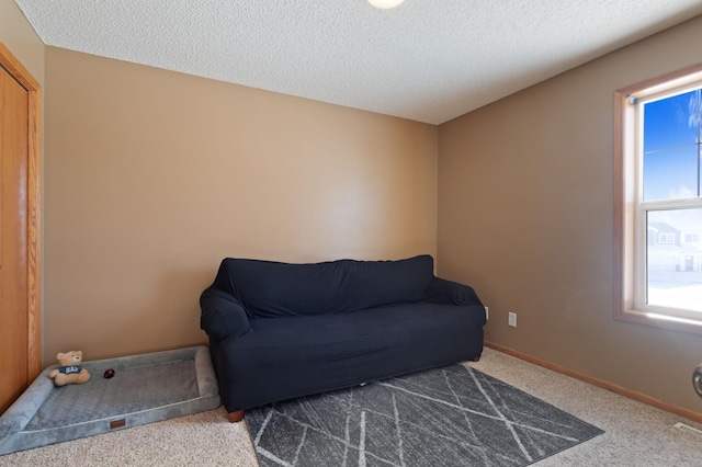 sitting room with a textured ceiling and dark colored carpet