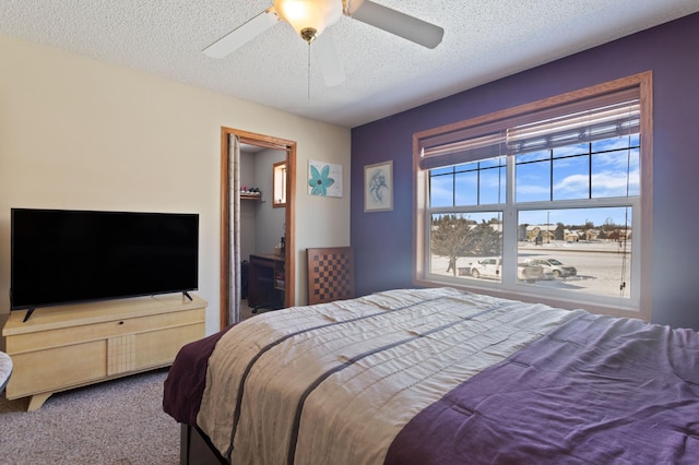 carpeted bedroom featuring ceiling fan, a spacious closet, and a textured ceiling