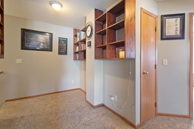 corridor featuring light carpet and a textured ceiling