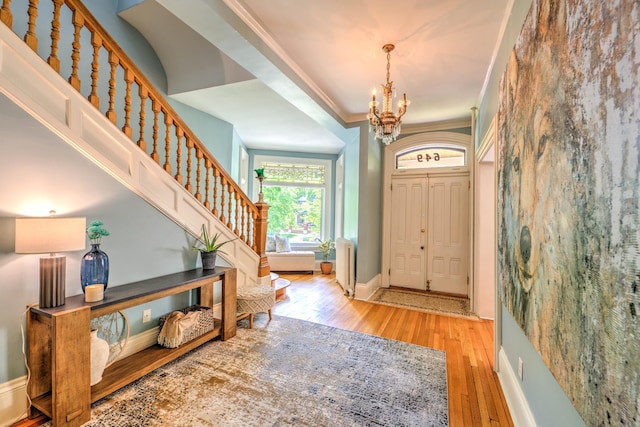 entryway featuring ornamental molding, a chandelier, and light wood-type flooring