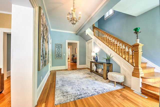 foyer with crown molding, a chandelier, and light hardwood / wood-style floors