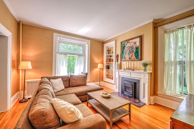 living room with crown molding, built in shelves, and light hardwood / wood-style flooring