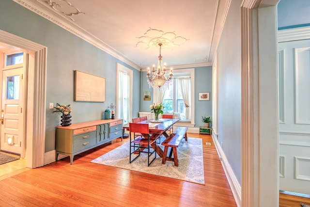 dining space featuring ornamental molding, a chandelier, and light hardwood / wood-style floors