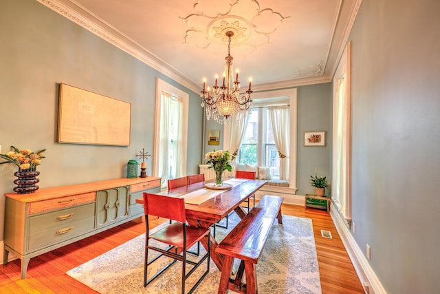 dining room with crown molding, a chandelier, and light hardwood / wood-style flooring