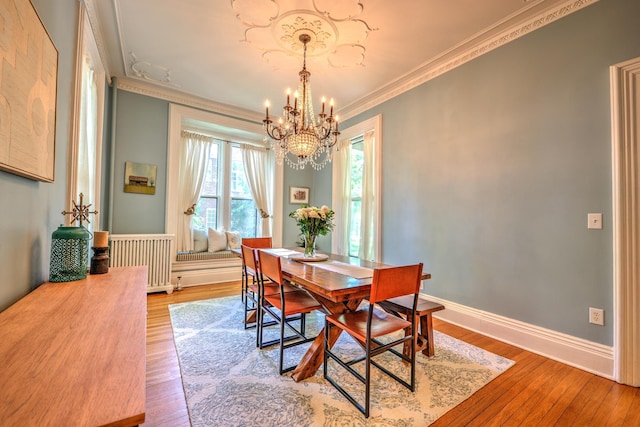 dining room with hardwood / wood-style floors, crown molding, radiator heating unit, and a chandelier