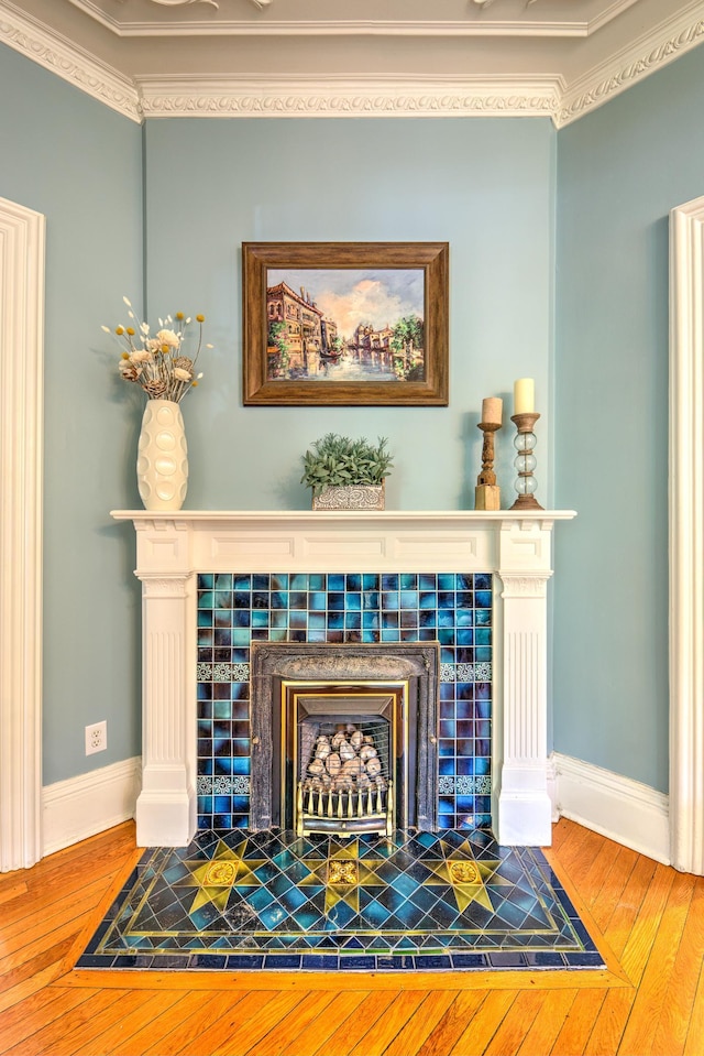 interior details with ornamental molding, hardwood / wood-style floors, and a fireplace