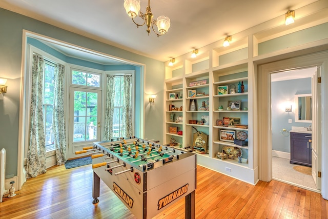 rec room featuring sink, built in features, a chandelier, and light hardwood / wood-style flooring