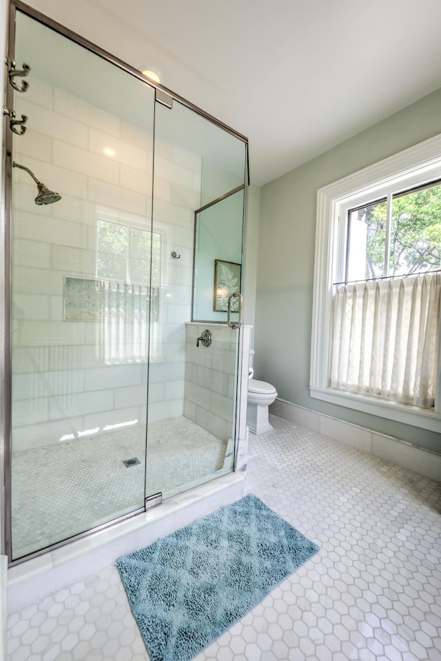 bathroom with tile patterned flooring, toilet, and a shower with shower door