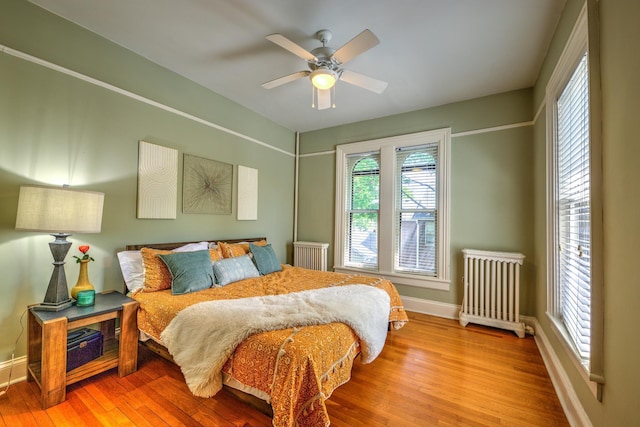 bedroom featuring radiator heating unit, ceiling fan, and light hardwood / wood-style flooring