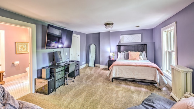 bedroom featuring ensuite bathroom and light carpet