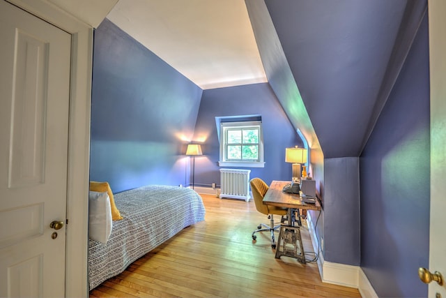 bedroom featuring lofted ceiling, radiator, and light hardwood / wood-style floors